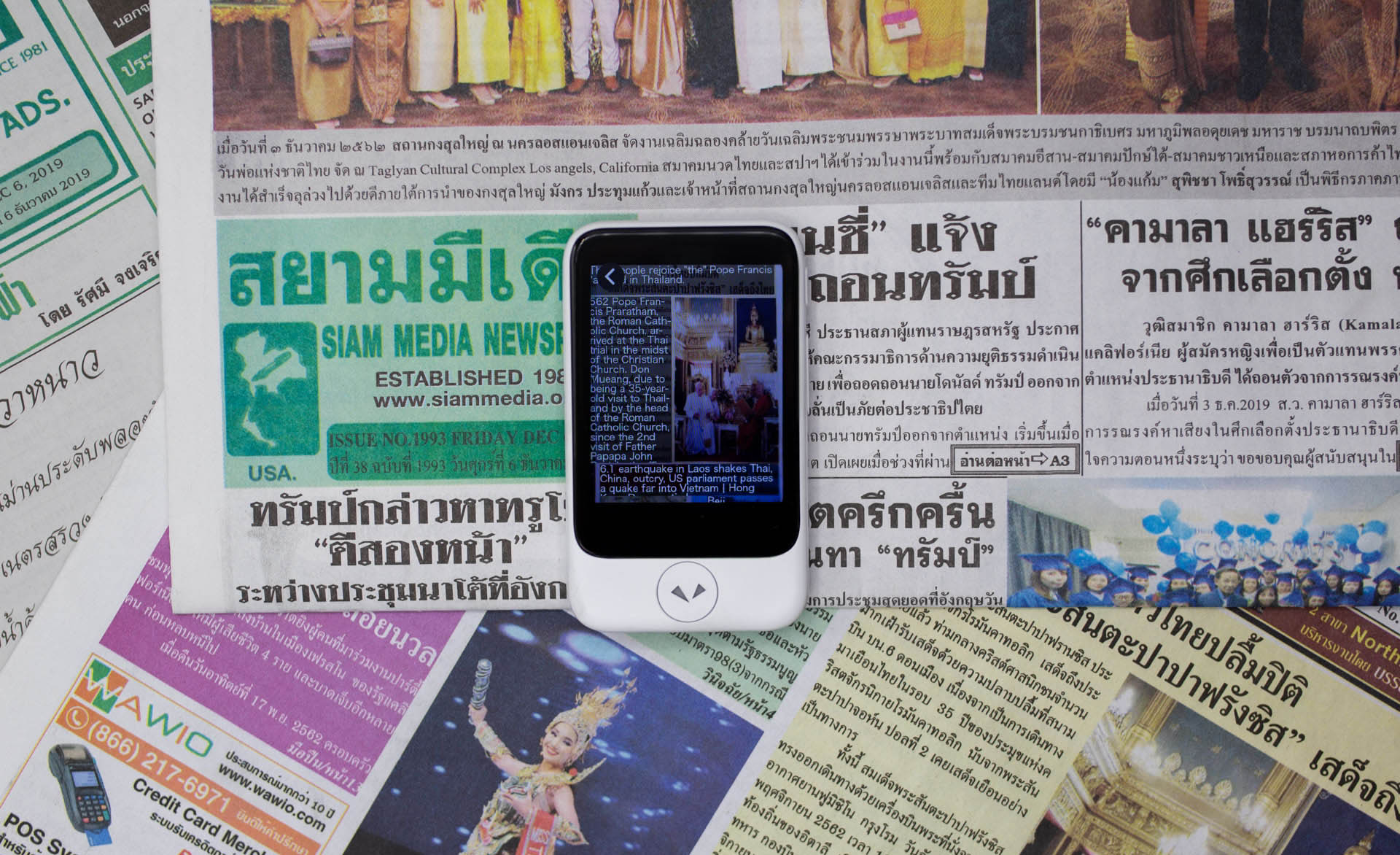 Pocketalk device on top of non-english news papers.